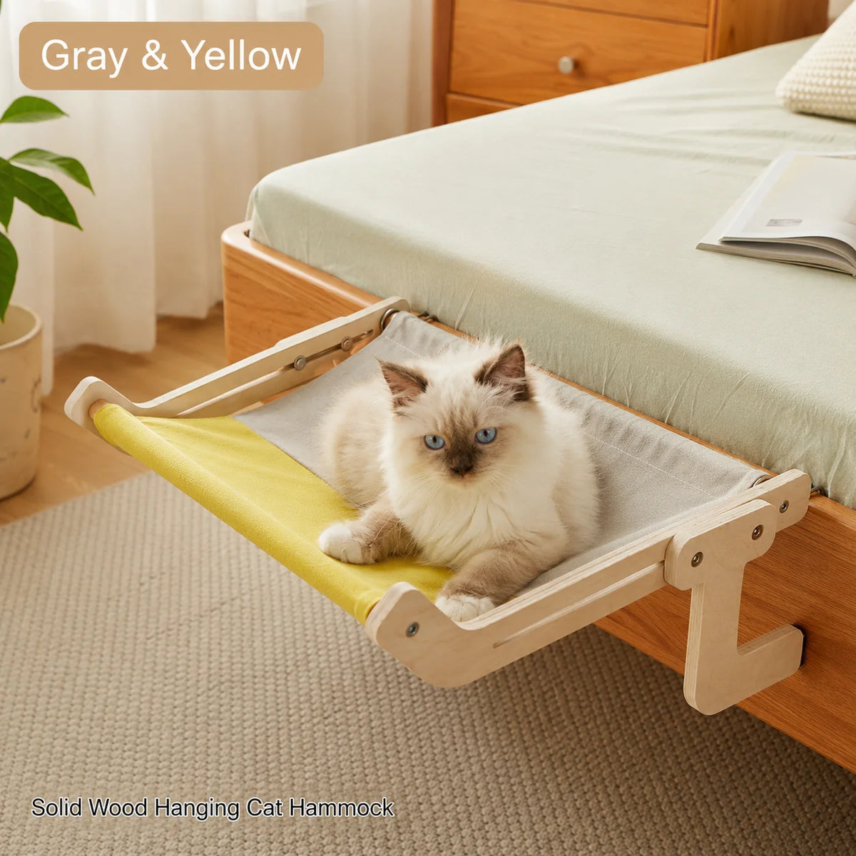 Gray and yellow wooden cat hammock attached to a bed frame with cat lounging